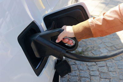 Cropped hand of person filling gasoline into car