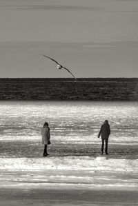 Men standing on beach against sky