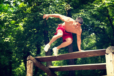 Full length of shirtless man exercising on wooden platform 