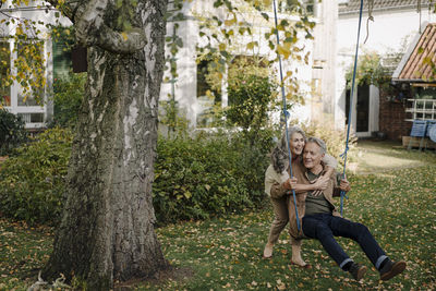 Happy woman embracing senior man on a swing in garden