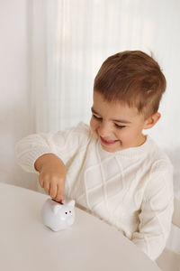 Little boy putting money coin into piggy bank for saving money. wealth, budget, investment, finance 