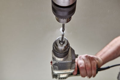 Close-up of hand holding faucet against water