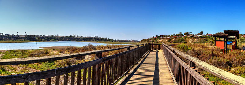 Empty footbridge against clear blue sky