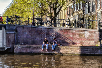 Rear view of people on canal amidst buildings