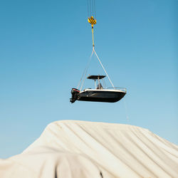 Low angle view of sailboat against building against clear blue sky