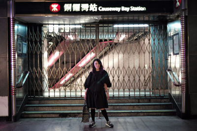 Full length portrait of woman standing in corridor