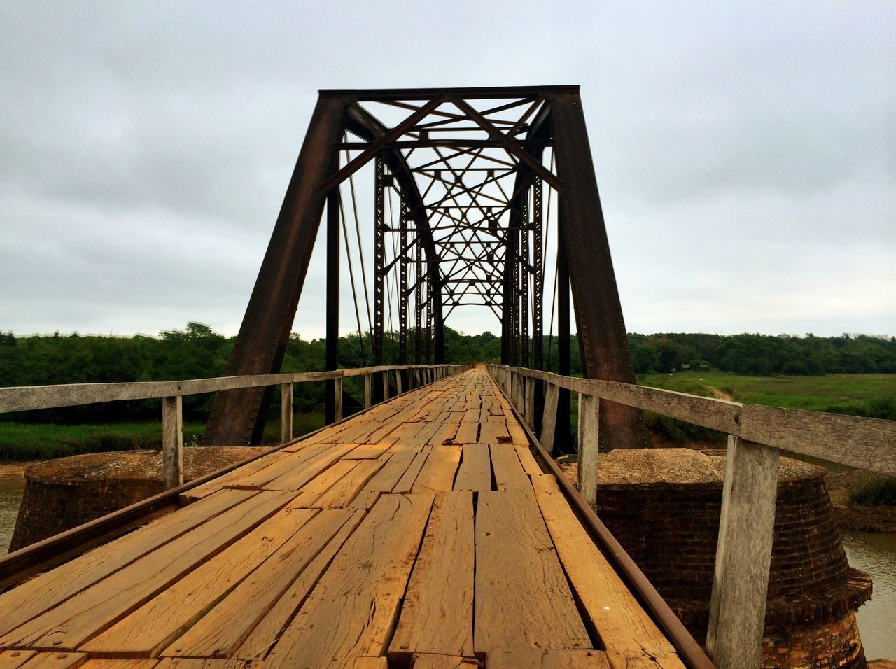 sky, the way forward, diminishing perspective, built structure, cloud - sky, connection, wood - material, architecture, vanishing point, cloudy, bridge - man made structure, transportation, metal, cloud, footbridge, day, railing, no people, tree, long