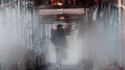 Rear view of man walking in bridge 