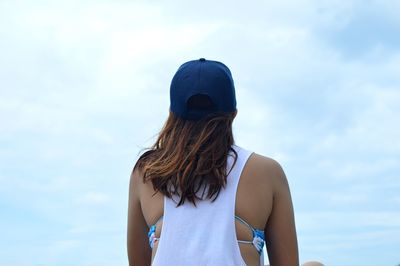 Rear view of woman sitting against cloudy sky