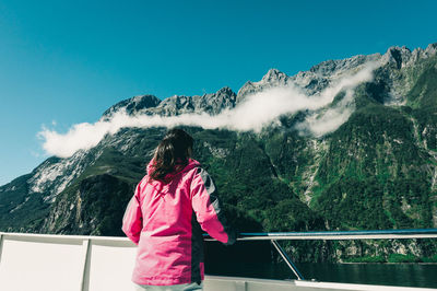 Rear view of woman looking at mountains against sky