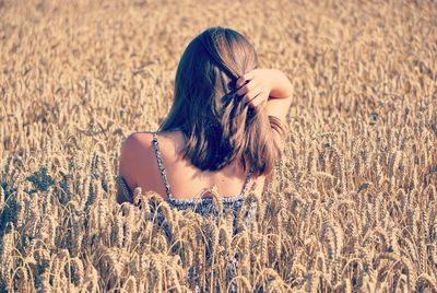 Rear view of woman amidst cereal plants on agricultural field