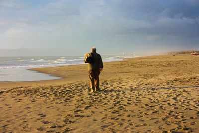 Rear view of man on beach against sky