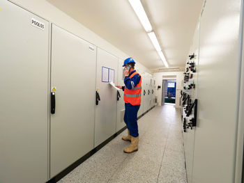 Calling worker. industrial engineer using phone in machin control room, controlling data on panel