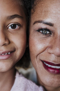 Close-up of smiling mother and daughter at home