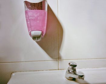 Soap dispenser mouthed on wall by sink in bathroom