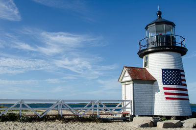 Lighthouse by sea against sky