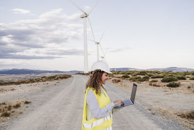 Smiling engineer working on laptop at wind farm