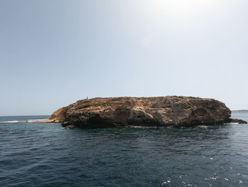 Rock formations by sea against clear sky