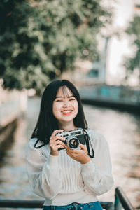 Portrait of a smiling young woman holding camera