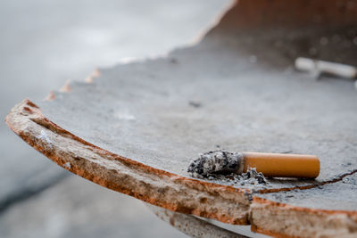 Close-up of cigarette butt on broken surface