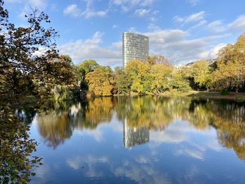 Reflection of trees and buildings in lake against sky