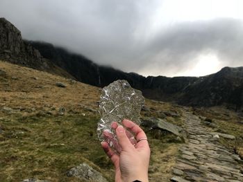 Cropped hand of woman holding ice against sky