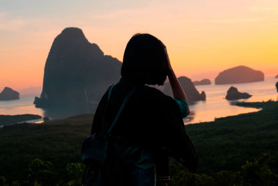 Man looking at sea against sky during sunset