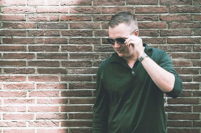 Full length of young man standing against brick wall