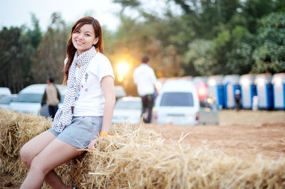 Portrait of smiling woman sitting on hay stack