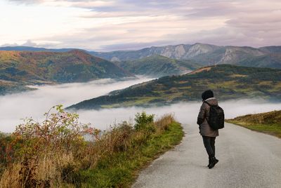 Rear view of woman looking at foggy mountain against sky