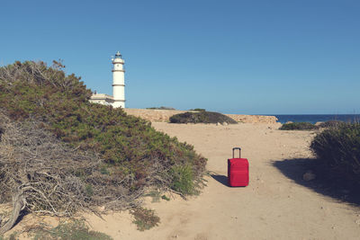 Lighthouse by sea against clear sky