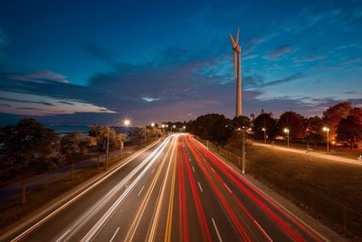 Light trails on road against sky at night