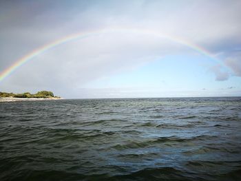 Scenic view of rainbow over sea against sky