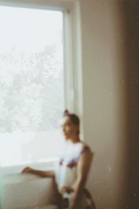 Side view of woman standing by window