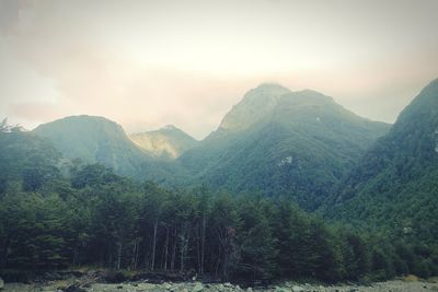 Scenic view of mountains in mist against sky