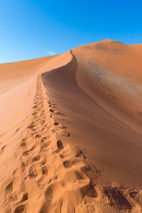 Sand dunes in desert against clear blue sky