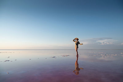 Evening view of the shallow salty pink lake. reflection. a young woman in a hat walks on the water