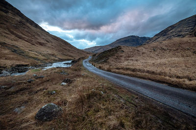 Scenic view of road by mountains against sky