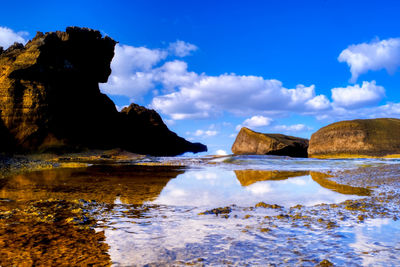 Scenic view of rocks by sea against sky