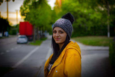 Portrait of smiling young woman standing on road in city