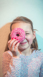 Close-up of girl holding donut in front of face