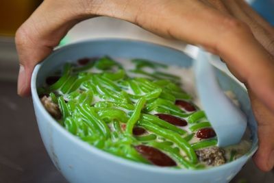 Close-up of hand holding cendol in bowl