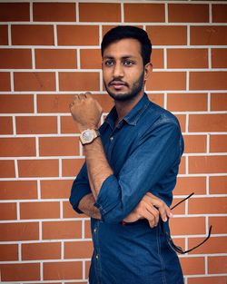 Young man sitting against brick wall