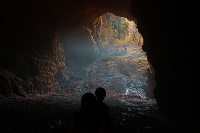 Rear view of silhouette woman standing in cave