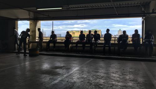 Group of people waiting at railroad station platform against sky