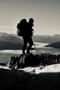 Silhouette man hiking on snowcapped mountain against sky