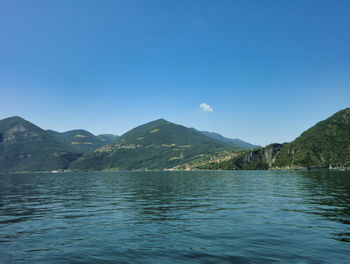 Scenic view of sea and mountains against clear blue sky