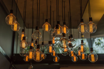 Low angle view of illuminated light bulbs hanging from ceiling