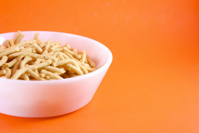 Close-up of pasta in bowl against orange background