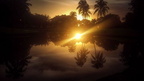 Silhouette trees by lake against sky during sunset